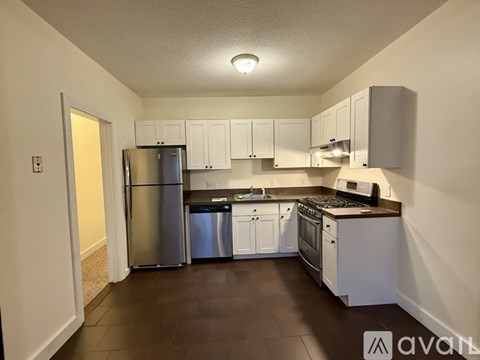 A kitchen with white cabinets and a stainless steel refrigerator.