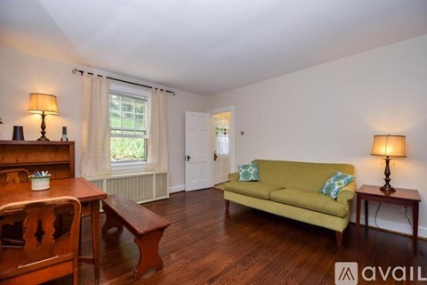 A living room with a green couch and wooden furniture.