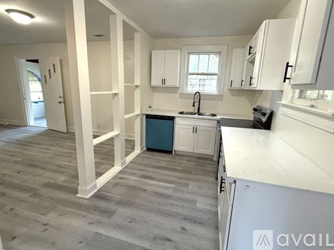 A kitchen with white cabinets and a grey floor.