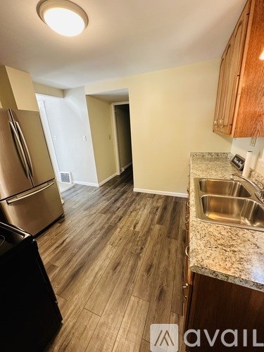 A kitchen with a stainless steel refrigerator and a sink with a granite countertop.