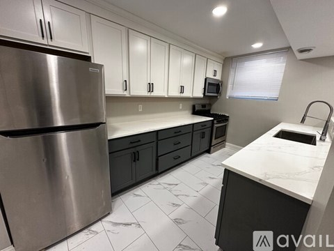 A kitchen with a stainless steel refrigerator and white cabinets.
