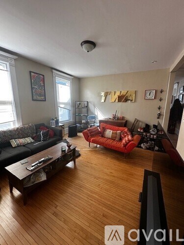 A living room with a red couch and a wooden floor.