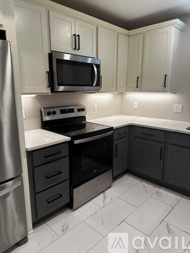 A kitchen with a stainless steel refrigerator and black appliances.