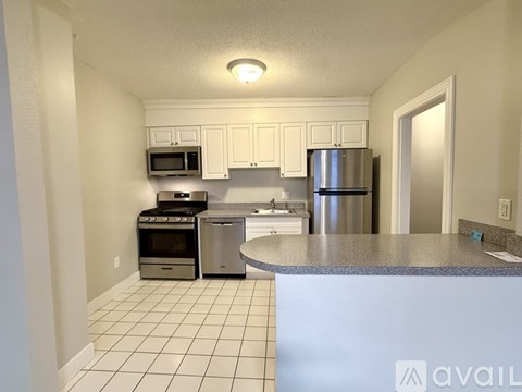 A kitchen with white cabinets and a stainless steel refrigerator.