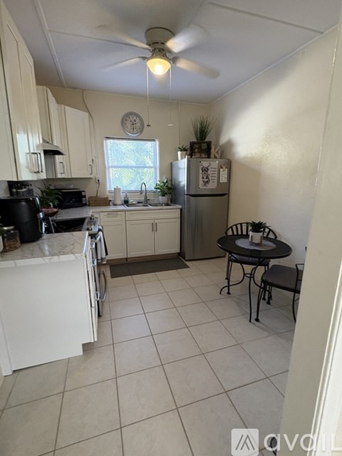 A kitchen with white cabinets and a black counter top.