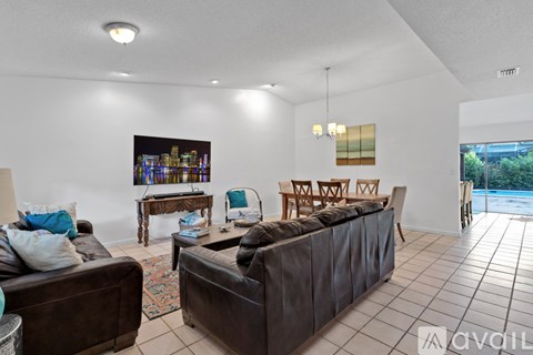 A living room with a brown couch and a table with a lamp on it.
