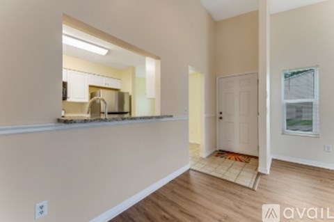 A kitchen with white cabinets and a window is visible from the living room.