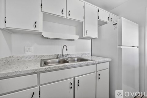 A kitchen with white cabinets and a marble countertop.