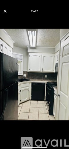 A kitchen with black appliances and white cabinets.