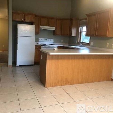 A kitchen with a white refrigerator and wooden cabinets.