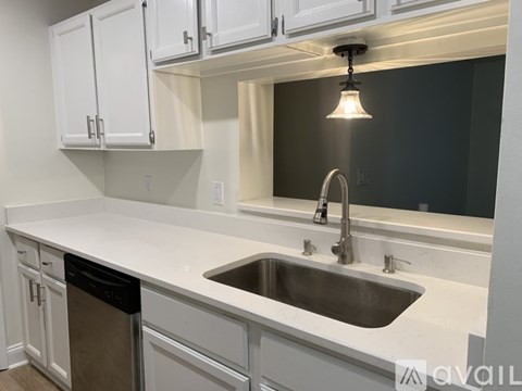 A kitchen with white cabinets and a stainless steel sink.