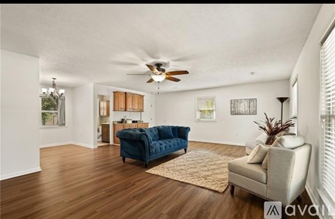 A living room with a blue couch and a fan on the ceiling.