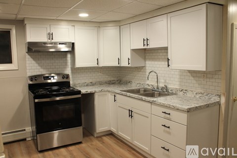 A kitchen with white cabinets and a marble countertop.