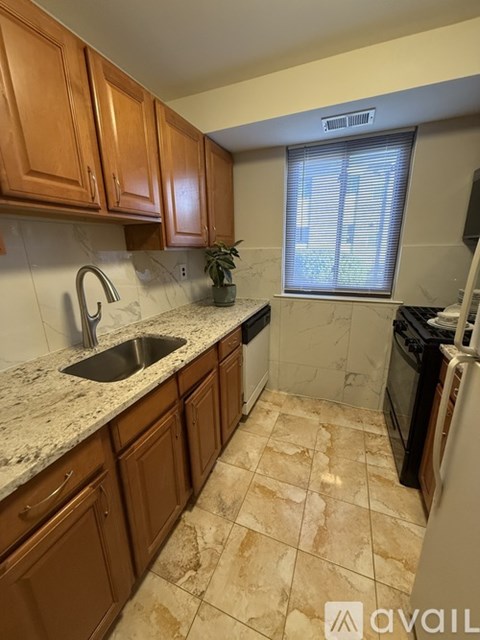 A kitchen with brown cabinets and a marble countertop.