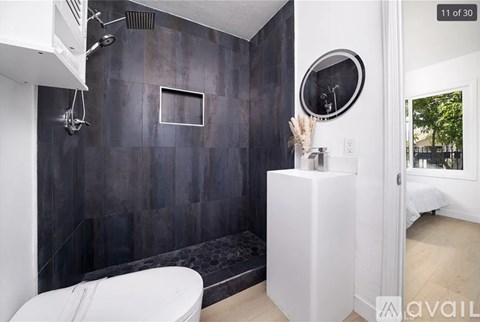 A modern bathroom with a white toilet and a round mirror on the wall.