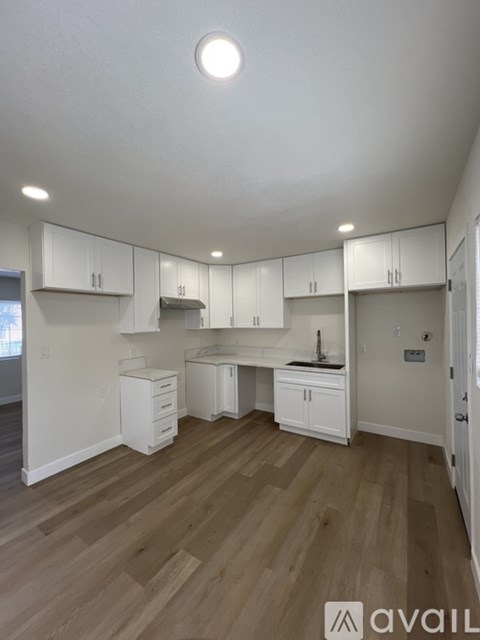 A kitchen with white cabinets and wooden floors.