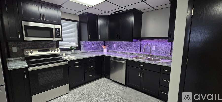 A kitchen with black cabinets and a grey floor.