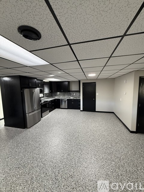 A kitchen with black cabinets and a grey floor.