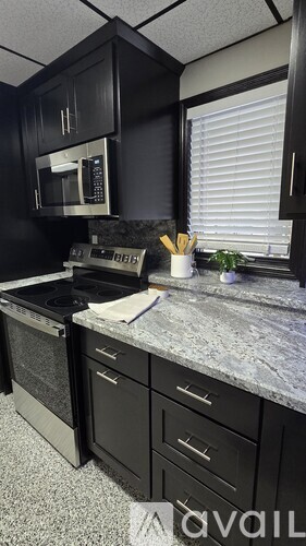 A kitchen with black cabinets and stainless steel appliances.