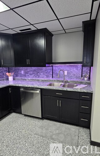 A spacious office room with a carpeted floor and a window on the right side.