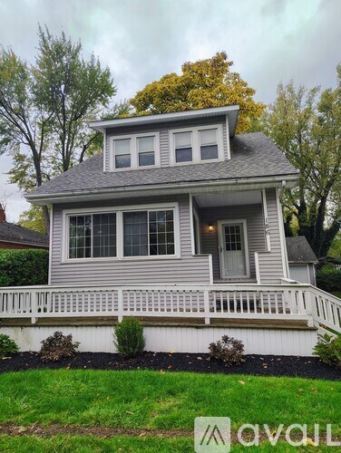 A house with a grey roof and white fence is for sale.