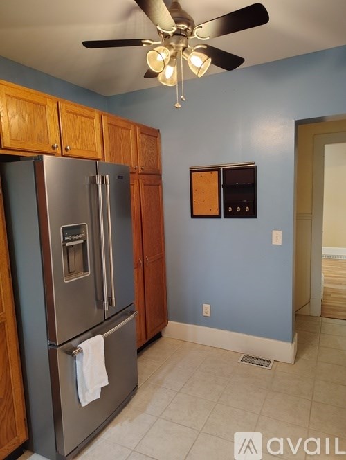 A kitchen with a stainless steel refrigerator and wooden cabinets.