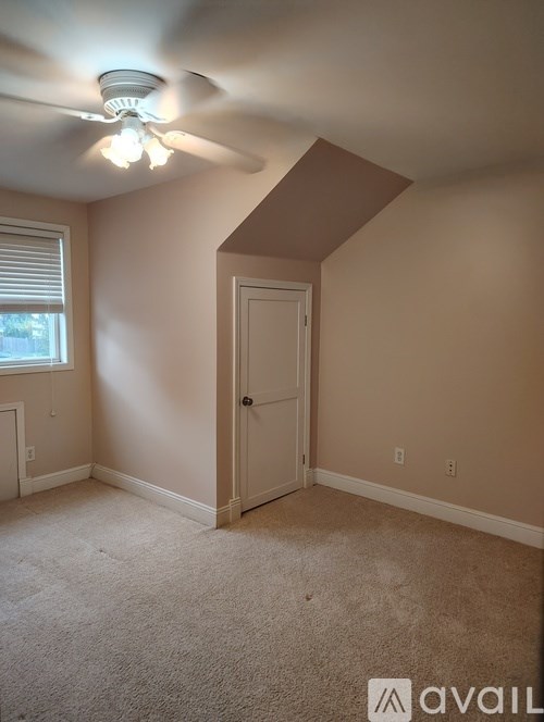 A room with a ceiling fan and a door.