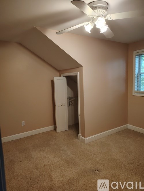 A room with a ceiling fan and a doorway leading to another room.