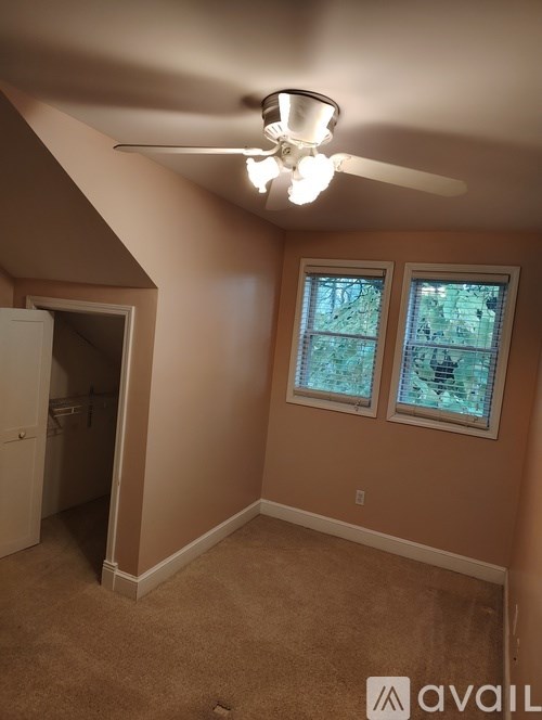 A room with a ceiling fan and two windows.
