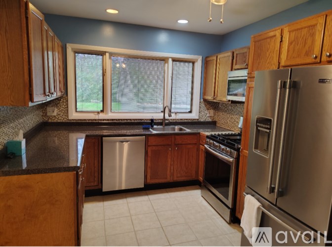 A kitchen with wooden cabinets and a stainless steel refrigerator.