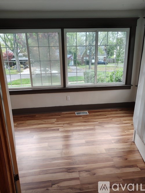 A room with a large window and wooden flooring.