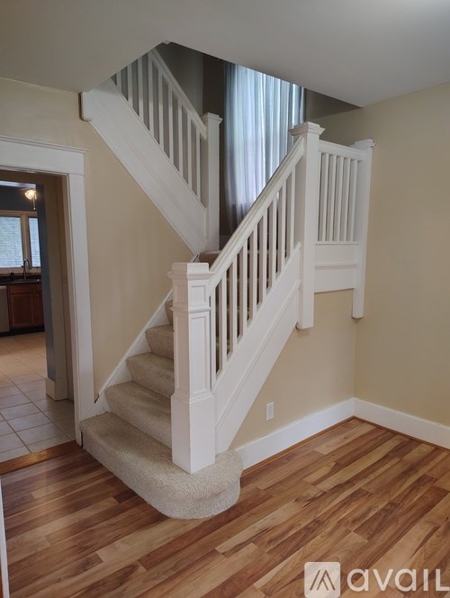 A staircase with a beige carpeted runner and white balusters.