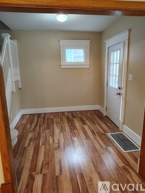 A room with wooden flooring and a white door.