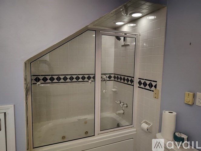 A bathroom with a glass shower door and a white bathtub.