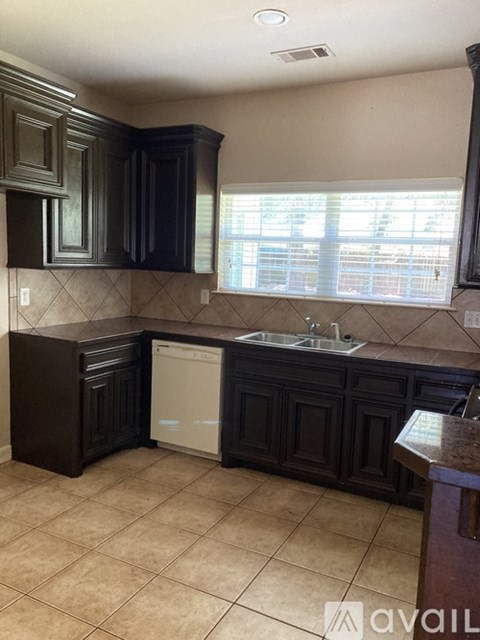 A kitchen with dark brown cabinets and a white dishwasher.