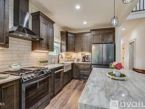 A kitchen with dark wood cabinets and a marble countertop.