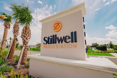 A sign for Stillwell Pasco Station with palm trees in the background.