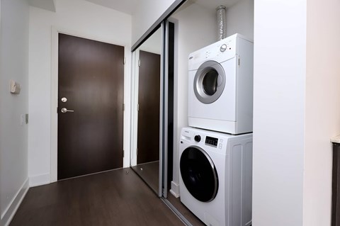A white dryer and washer are stacked on top of each other in a small room.