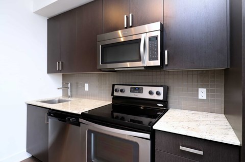 A modern kitchen with dark brown cabinets and stainless steel appliances.
