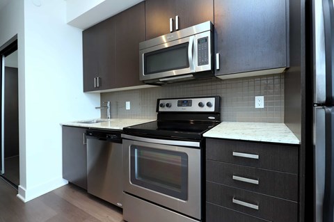 A modern kitchen with dark brown cabinets and stainless steel appliances.
