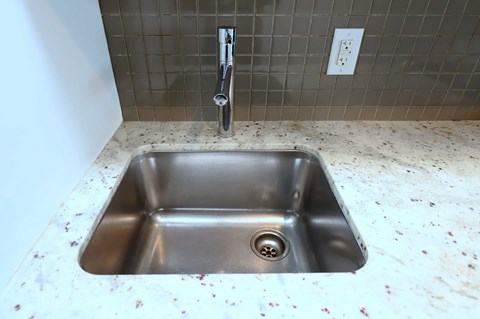 A dirty sink in a bathroom with a silver faucet.