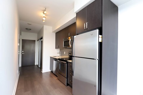 A kitchen with a refrigerator, oven, and microwave.