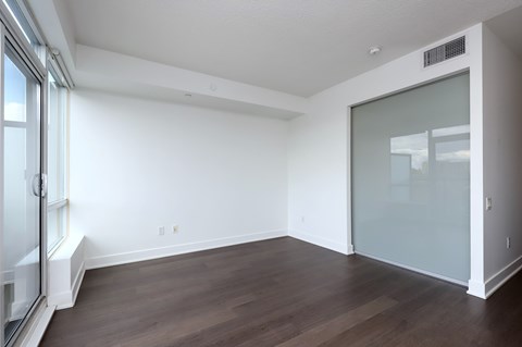 A room with a sliding glass door and wood flooring.