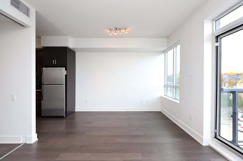 A spacious kitchen with a refrigerator and a window overlooking the street.