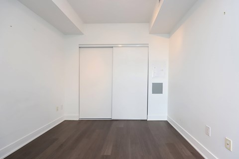 A room with a white door and a brown floor.