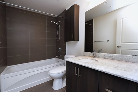 A white toilet sits next to a white bathtub in a bathroom.