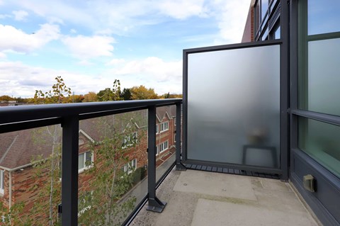 A balcony with a glass door and a black railing.