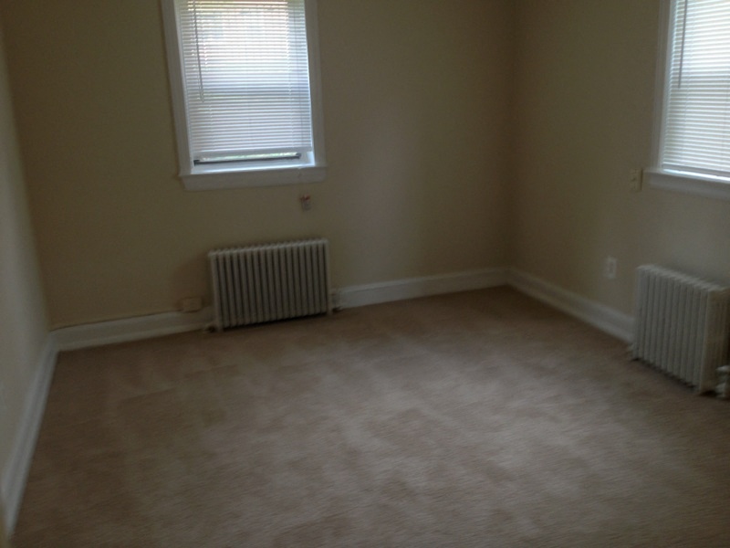 an empty room with two radiators and two windows
