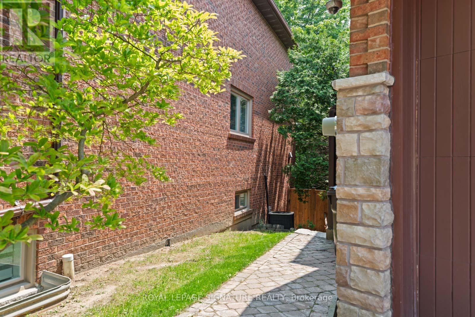 A tree with green leaves is in front of a brick building.
