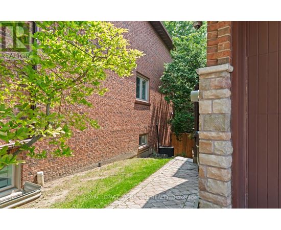 A tree with green leaves is in front of a brick building.